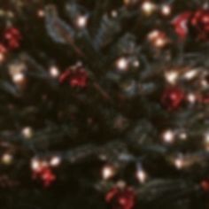 a christmas tree is decorated with red and white ornaments on it's branches, while the lights shine brightly in the background