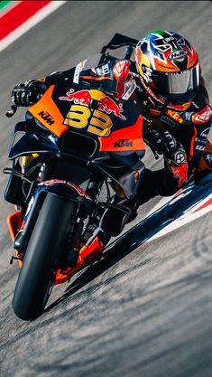 a man riding on the back of a motorcycle down a race track in an orange and black outfit