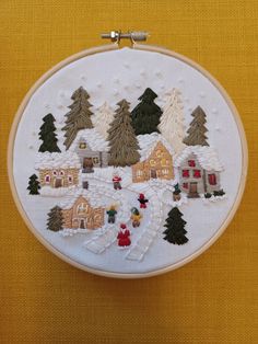 a cross stitch pattern with houses and trees in the snow on a yellow cloth background