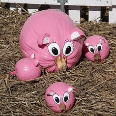 three pink toys sitting on top of straw covered ground