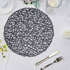 the table is set with silverware and white linens, along with an intricately designed placemat