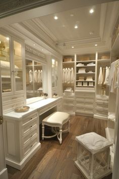 a walk in closet with white cabinets and drawers