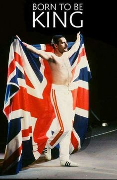 a shirtless man holding a british flag in front of his face and chest while standing on stage