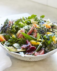 a white bowl filled with greens and fruit