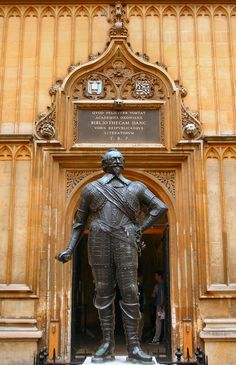 a statue of a man standing in front of a building with an arched doorway and gold walls