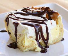 a piece of cake covered in chocolate sauce and whipped cream on a square white plate