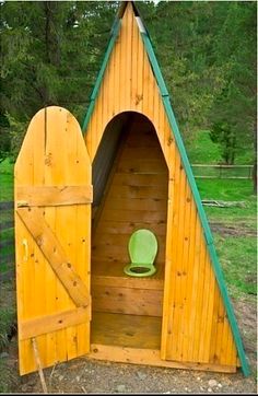 a toilet in a wooden structure with a green seat on the outside and side doors open