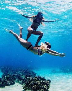 two women in bikinis are diving under the water