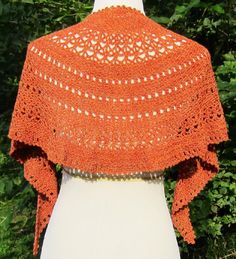 an orange crocheted shawl on top of a white mannequin