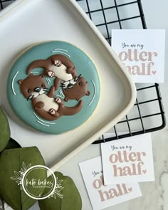 two otters are in the water on top of a cookie that is sitting on a plate