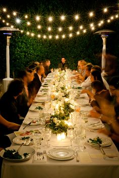 a group of people sitting at a long table with plates and glasses in front of them