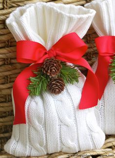 a white sweater wrapped in red ribbon with a pine cone on top