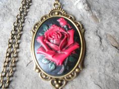 For sale are red rose with black through and green leaves and stem, cameo pendant necklaces!!!!  Gorgeous unique colors, each individually hand painted, each an original!!! 2" long!!!  They are offered at a reasonable price, make perfect gifts, and are wonderful quality!!!!  Timeless and Classic look!!!  The cameo is set in a bronze setting, and the chain is 24" adjustable rolo link chain, with a lobster claw clasp!!!!  I make several varieties, colors, styles and matching sets!!!!  I will be gl Gothic Rose-colored Jewelry For Gifts, Gothic Rose Colored Jewelry For Gift, Gothic Rose Jewelry For Gift, Rose-colored Gothic Jewelry For Gift, Red Cameo Necklace For Gift, Vintage Black Necklace For Valentine's Day, Black Necklace With Rose Design As Gift, Black Necklace With Rose Design For Gift, Gothic Cameo Necklaces For Gifts