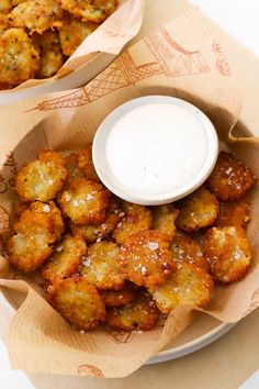 two baskets filled with fried food next to a bowl of ranch dressing and dipping sauce