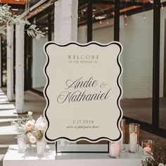 a welcome sign sitting on top of a white table next to candles and vases