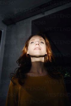 a woman standing in the dark looking up into the sky with her eyes wide open