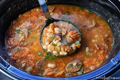 a ladle full of soup with beans and sausage in the slow - cooker