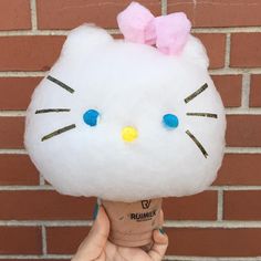 a person holding up an ice cream cone with hello kitty on it's head