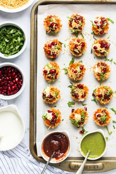 small appetizers are arranged on a baking sheet with dipping sauces and condiments