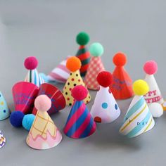 small party hats with pom poms on them are arranged in a row and one is brightly colored