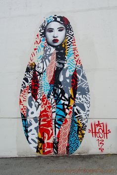 a large painting on the side of a building with words written all over it and a woman's face