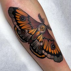 an orange and black butterfly tattoo on the right arm, it has two eyes that look like moths