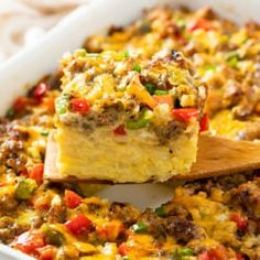 a casserole dish with meat, cheese and vegetables in it on a wooden spoon