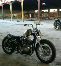 two motorcycles parked next to each other in an empty parking lot with graffiti on the walls