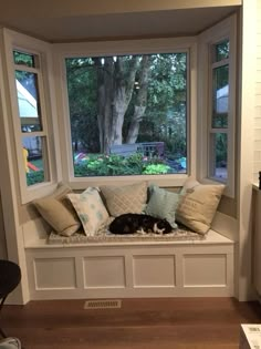 a black and white cat sleeping on a window sill in front of a tree