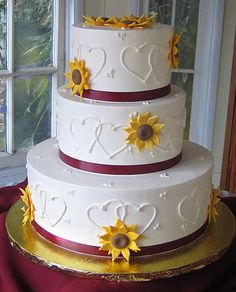 a wedding cake decorated with sunflowers and hearts