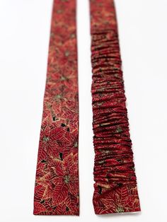 two pieces of red and gold cloth with leaves on them, one is folded to the side