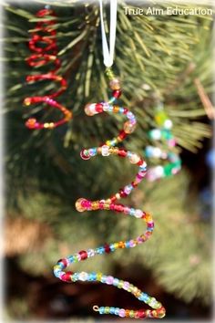 an ornament hanging from a christmas tree with beads and streamers on it