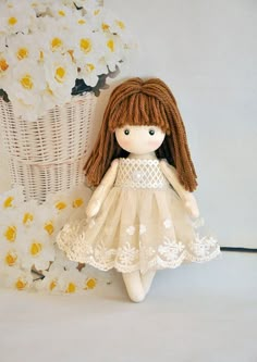 a little doll sitting next to a basket with flowers on the wall in front of it