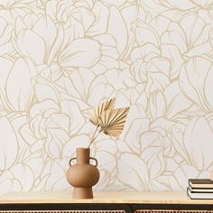 a vase sitting on top of a wooden table next to a wallpaper covered in flowers