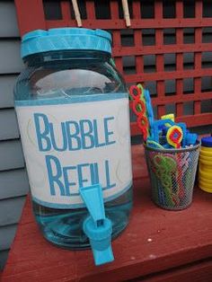 there is a plastic jar with bubbles in it sitting on a bench next to some cups