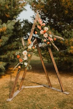 an arch decorated with flowers and feathers for a wedding ceremony in the woods, surrounded by pine trees