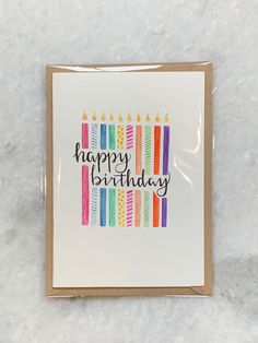 a happy birthday card with colorful candles on the front, and an envelope that says happy birthday