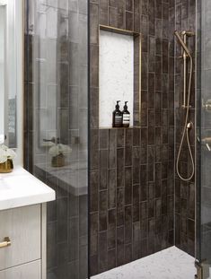 a walk in shower sitting next to a white sink and counter top under a mirror