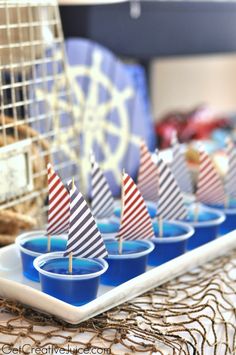 there are many small sailboats on the trays with blue cups in front of them