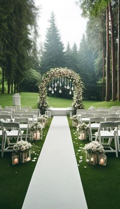 an outdoor ceremony setup with white chairs and flowers on the aisle, surrounded by candles