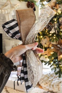 a person holding up a ribbon in front of a christmas tree