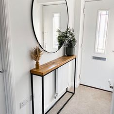 a mirror on the wall next to a table with a potted plant