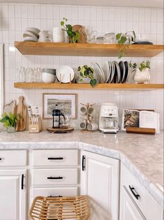 a kitchen with white cabinets and shelves filled with plates, cups and utensils