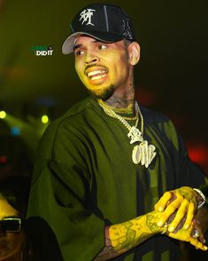 a man with tattoos on his arm and wearing a baseball cap is standing in front of a crowd