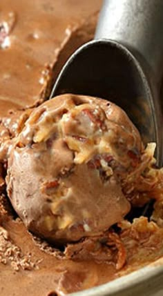 a scoop of ice cream is being scooped from a bowl with chocolate and pecans