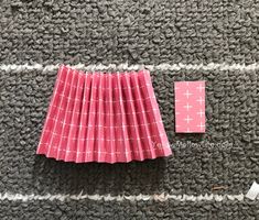 some pink and white paper sitting on top of a gray carpet next to a piece of cloth