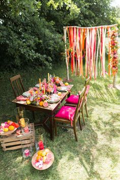 an outdoor table set up for a party with fruit and candles on it, along with other decorations