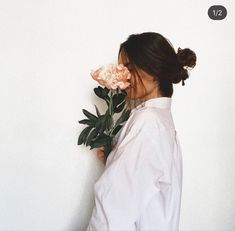 a woman holding flowers in her hands and looking at the wall behind her is an instagram