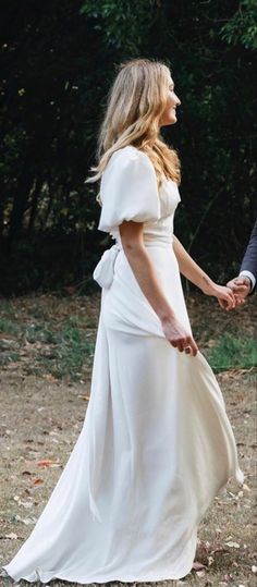 a woman in a white dress holding hands with a man