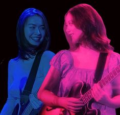 two young women are playing guitar together in the dark, one is wearing a pink dress